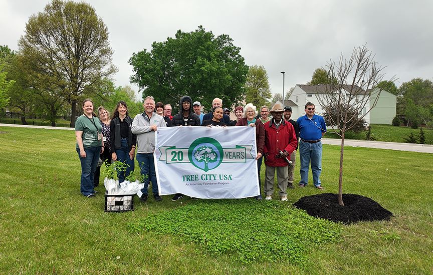 A group standing by a newly planted tree on Arbor Day